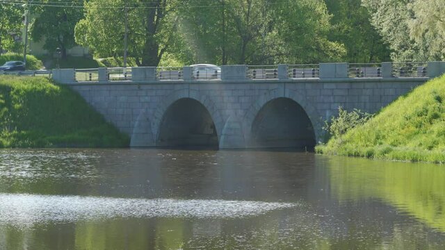 Stone bridge Marienthal pond Slavyanka river in Pavlovsk park on sunny spring day, Saint Petersburg, Russia.