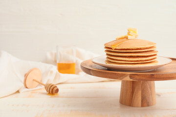 Tasty pancakes with honey and butter on table