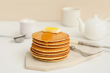Tasty pancakes with butter and honey on table