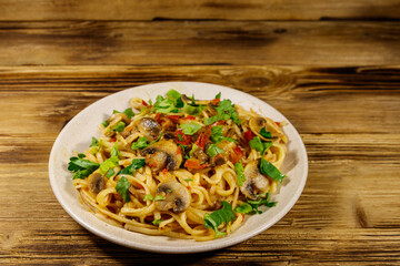 Pasta with mushrooms and tomato sauce on wooden table