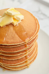 Tasty pancakes with butter and honey on table, closeup