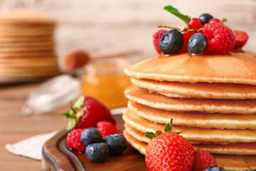 Sweet pancakes with berries on table, closeup