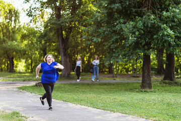 Plus size blonde girl jogging in the park. Concept on a healthy lifestyle and eliminating the...