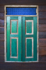 Wood vintage window with green shutters on the wooden wall