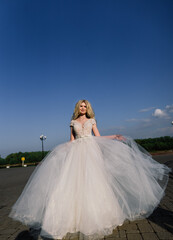 Fototapeta na wymiar Young attractive blonde bride with curly hair walking in the park and smiling