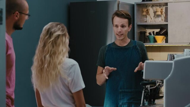 Back view of customers couple making order or buying coffee from barista in  stylish coffee shop. Small business and service concept&nbsp;
