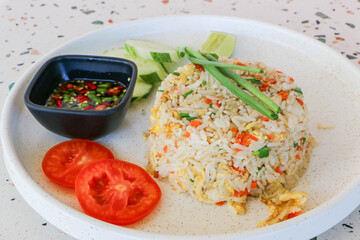 Crab fried rice, decorated with cucumbers and tomatoes on a white plate