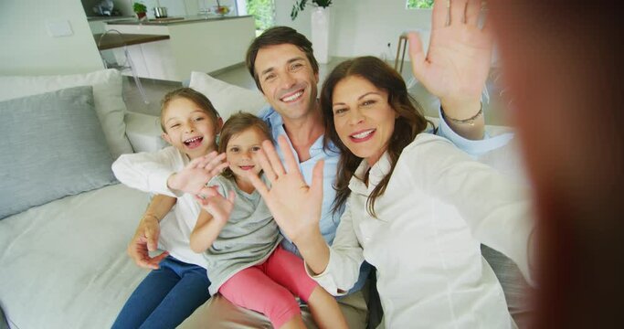 Authentic shot of happy smiling family are making a selfie or video call to friends or relatives on a sofa in a living room.