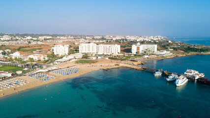 Fototapeta na wymiar Aerial bird's eye view of Sunrise beach Fig tree, Protaras, Paralimni, Famagusta, Cyprus.The famous tourist attraction family bay with golden sand, boats, sunbeds, restaurants, water sports from above