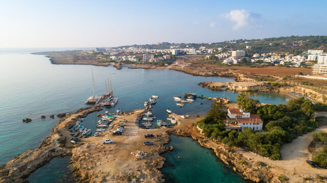 Aerial bird's eye view of Green bay in Protaras, Paralimni, Famagusta, Cyprus. Famous tourist attraction diving location rocky beach with boats, sunbeds, sea restaurants, water sports from above.