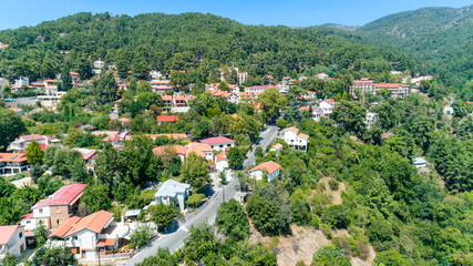 Fototapeta na wymiar Aerial view of Pano Platres village,winter resort, on Troodos mountains, Limassol, Cyprus. Bird's eye view of pine tree forest, red roof tiled houses, hotels, panagias faneromenis church from above.