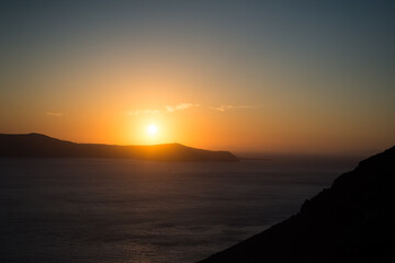 Sunset over the sea and the south end of the island of Santorini, Greece. View from Fira, the capital