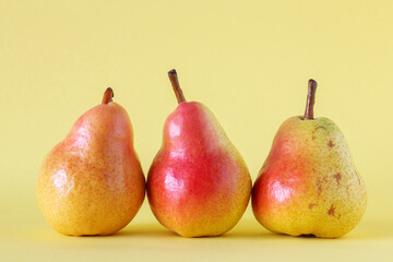 Three ripe pears on yellow background.