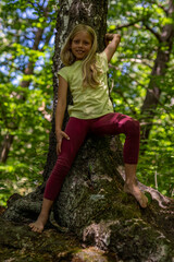 Mädchen beim unbeschwerten Sport und turnerischer Bewegen, wie Akrobatik in der Freizeit, im Wald und in der Natur. Sie trägt legere Kleidung, Shirt und Leggins.