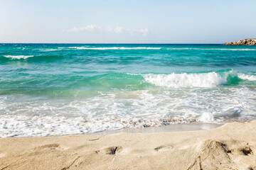 Turquoise sea with foamy waves on a sandy beach. Tourism and travel. Space for text.