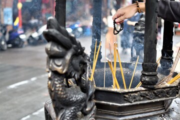 A worshipper uses beads to pray as incense sticks burn in a Chinese temple