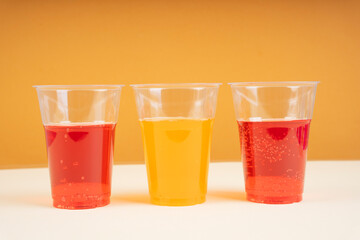 Two plastic red sparkling soda water cup and orange.