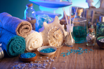 Spa and wellness concept. Bottles with cosmetics, rolled up towels, bath salts and care products on wooden paneling.