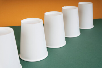 Up side down group of paper cup on green table.