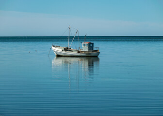 seascape with a small boat in calm water, sunny summer day, reflections in the water, Sorve Peninsula, Estonia