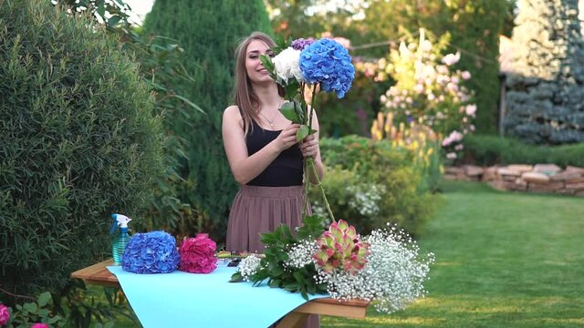 florist girl prepares a bouquet of hydrangeas in a beautiful garden