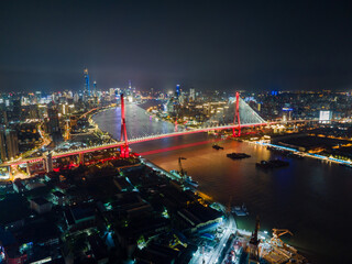 Naklejka premium Aerial view of Shanghai cityscape & night-scape. Futuristic modern city view. Downtown Lujiazui District and Yangpu bridge in the night. Neon light and traffic lights. Drone point of view in sky