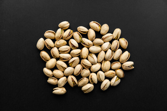 Pistachios scattered on a black table. Pistachio is a healthy vegetarian protein nutritious food. Natural nuts snacks.