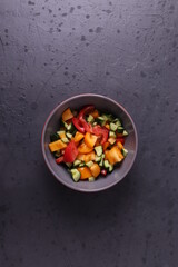 a bowl of vegen vegetable salad on  dark grunge stone background