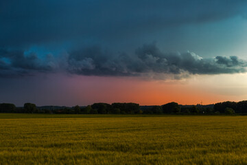 Storm atmosphere over wheat fields with cloudy sky and view of Inningen near Augsburg