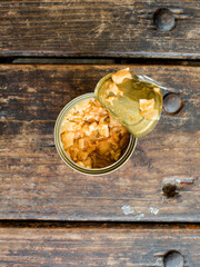 Top view of a partially opened can of corned chicken on top of a wooden bench.