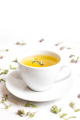 A Cup of tea with thyme flowers on a white background. The view from the top. Concept of folk medicine. Herbal drink.