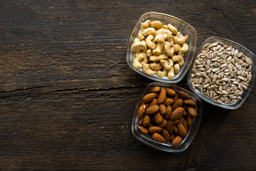 Almond, sunflower seeds and cashew in a small plates which standing on a vintage wooden table. Nuts is a healthy vegetarian protein and nutritious food.