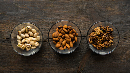 Almond, sunflower seeds and cashew in a small plates which standing on a vintage wooden table. Nuts is a healthy vegetarian protein and nutritious food.