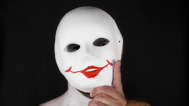 A mime man in a white mask depicts emotions. Man on a black background. High quality 4k footage