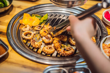 Woman grilling barbecue on mesh grill of charcoal fire. Korean or japanese traditional food grilling style barbecue
