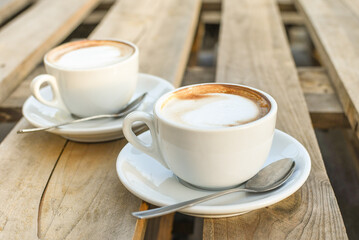 Two cups of cappuccino on wooden background. morning coffee for couple in love. selective focus