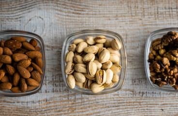Almond, pistachio and walnut in a small plates which standing on a vintage white table. Nuts is a healthy vegetarian protein and nutritious food.
