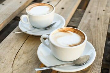 Two cups of cappuccino on wooden background. morning coffee for couple in love. selective focus