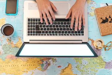 Top view female hands using laptop on world map booking next travel destinations - Young trip agent...