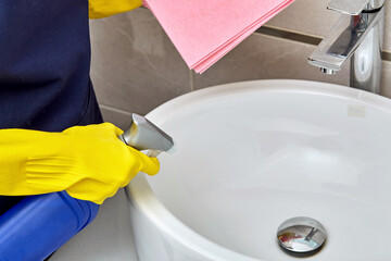 Girl washes a white sink in the bathroom. House cleaning.