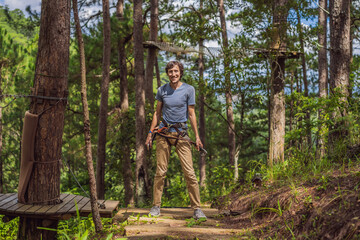 Naklejka premium Young attractive man in adventure rope park in safety equipment