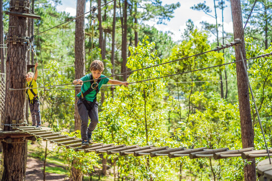 Portrait of cute little boy walk on a rope bridge in an adventure rope park