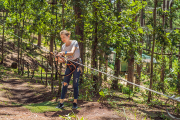 Young attractive woman in adventure rope park in safety equipment