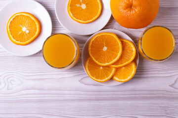 sliced fresh citruses and orange juice on the light rustic wooden surface. top view