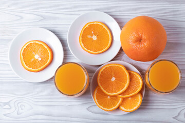 sliced fresh citruses and orange juice on the light rustic wooden surface. top view