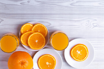 sliced fresh citruses and orange juice on the light rustic wooden surface. top view