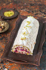 Homemade meringue roll with pistachios berry jam and cream cheese filling.