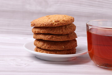 black tea in a glass cup and cookies on the light wooden surface