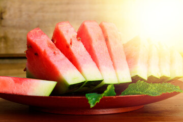 A row of fresh watermelon slices on a wooden plate.
