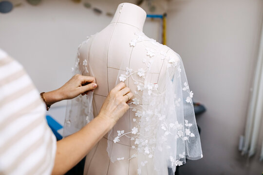 Work process of a tailor in her studio. Adjusting bridal dress process, lace gown on mannequin.
